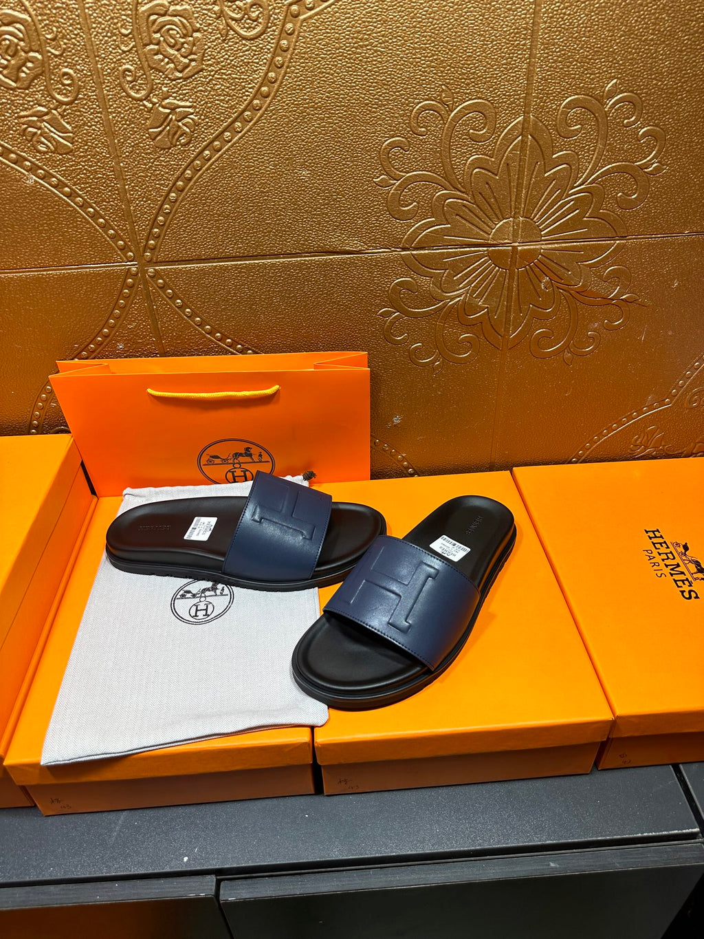 Leather slide sandals with wide front strap and stitched H detail on dark sole