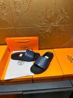 Leather slide sandals with wide front strap and stitched H detail on dark sole