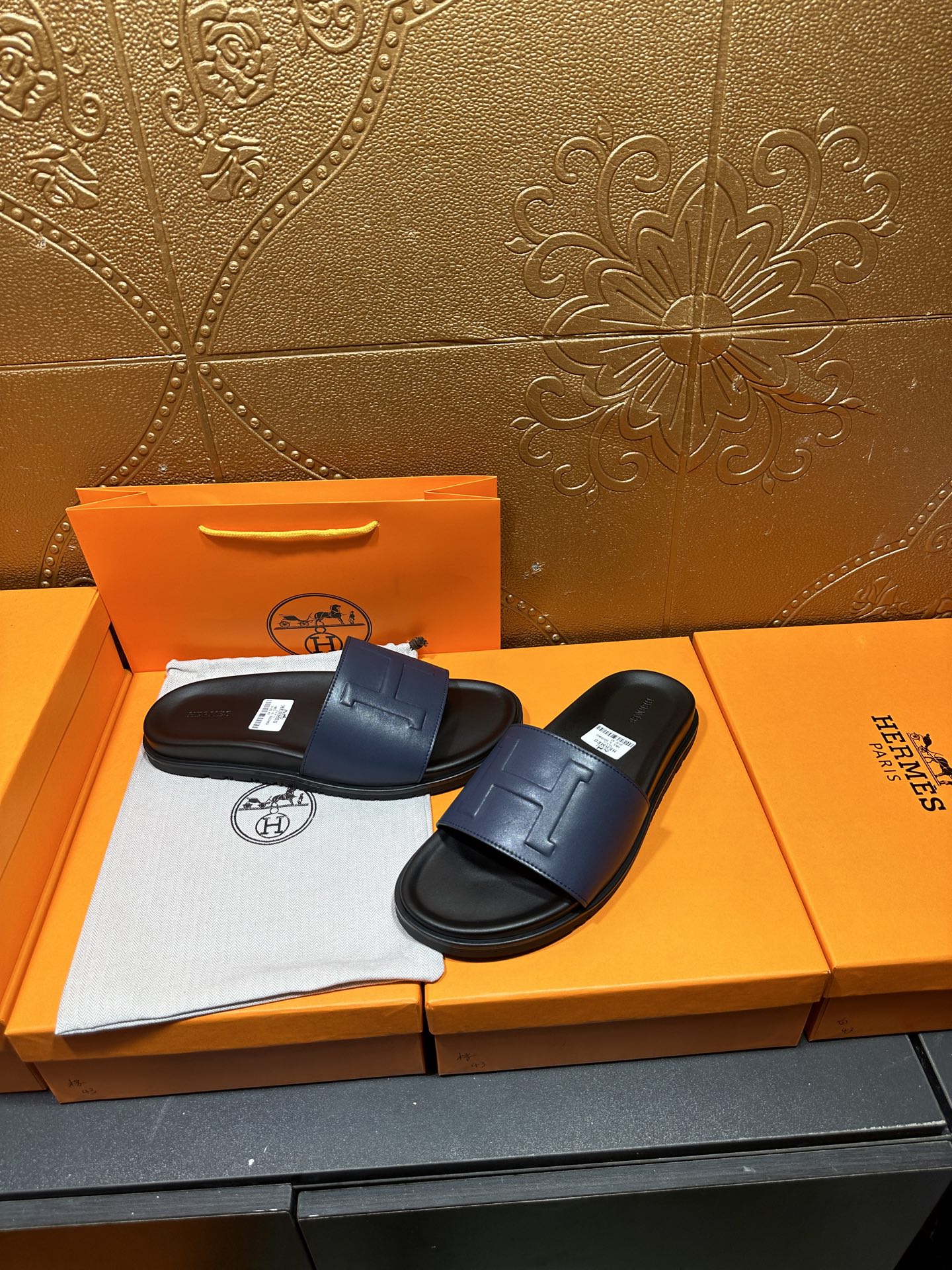 Leather slide sandals with wide front strap and stitched H detail on dark sole