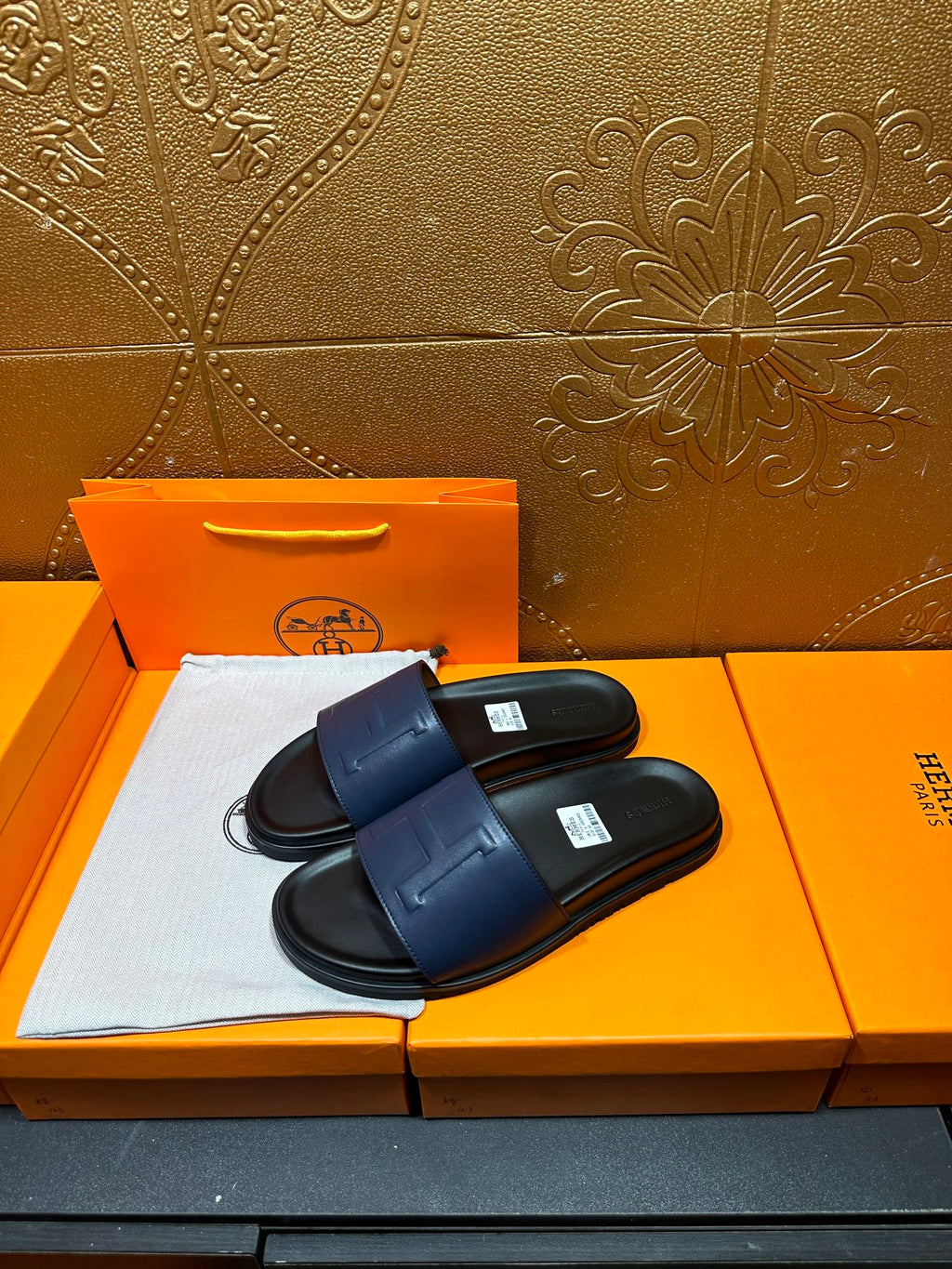 Pair of leather slide sandals with wide front strap and H-shaped stitch detail