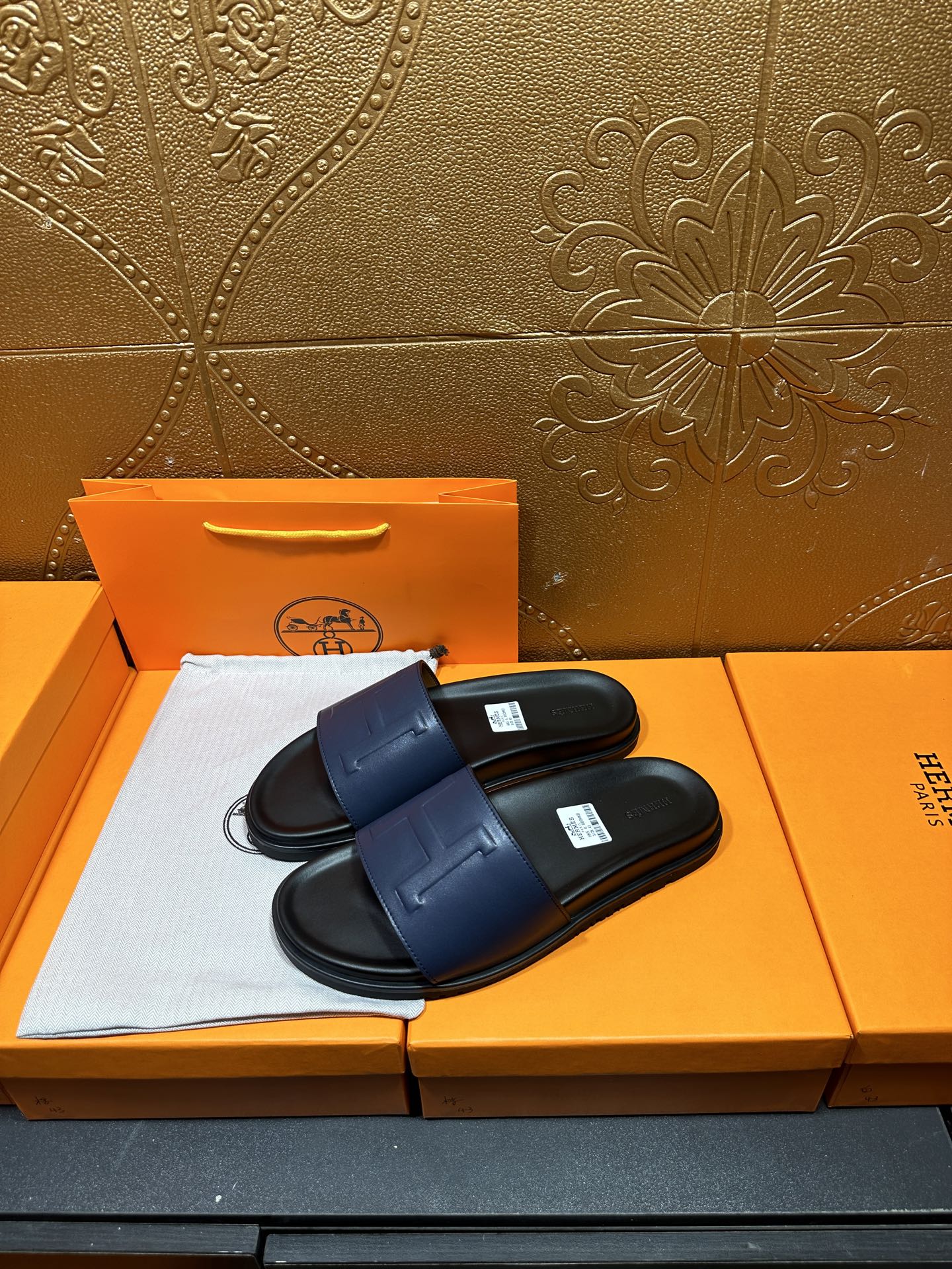 Pair of leather slide sandals with wide front strap and H-shaped stitch detail