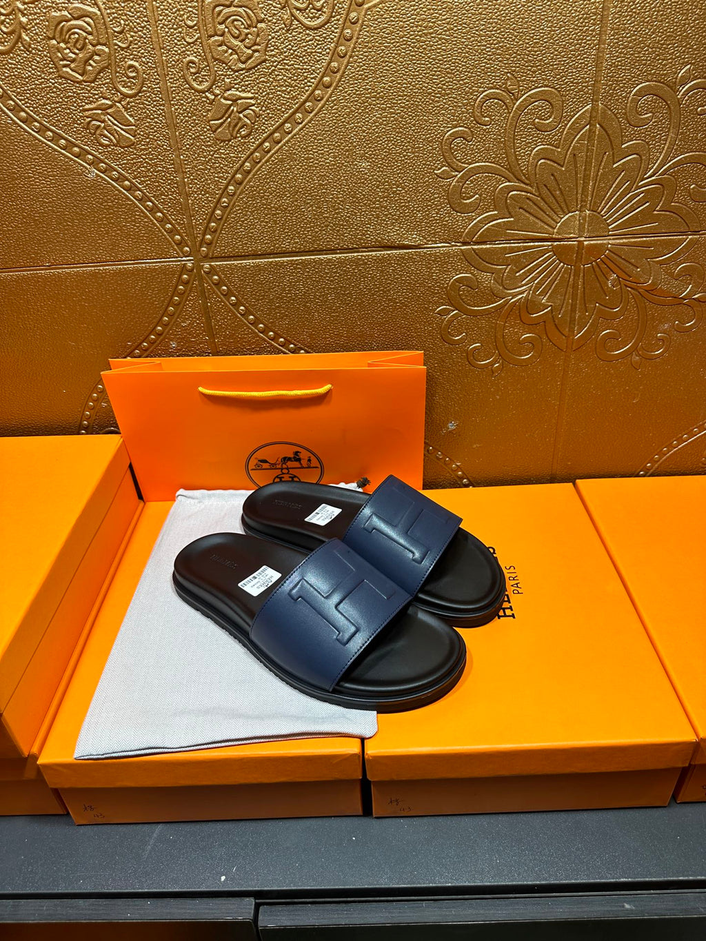 Leather slide sandals with broad strap, H stitch detail, and black footbed