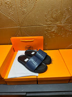 Leather slide sandals with broad strap, H stitch detail, and black footbed