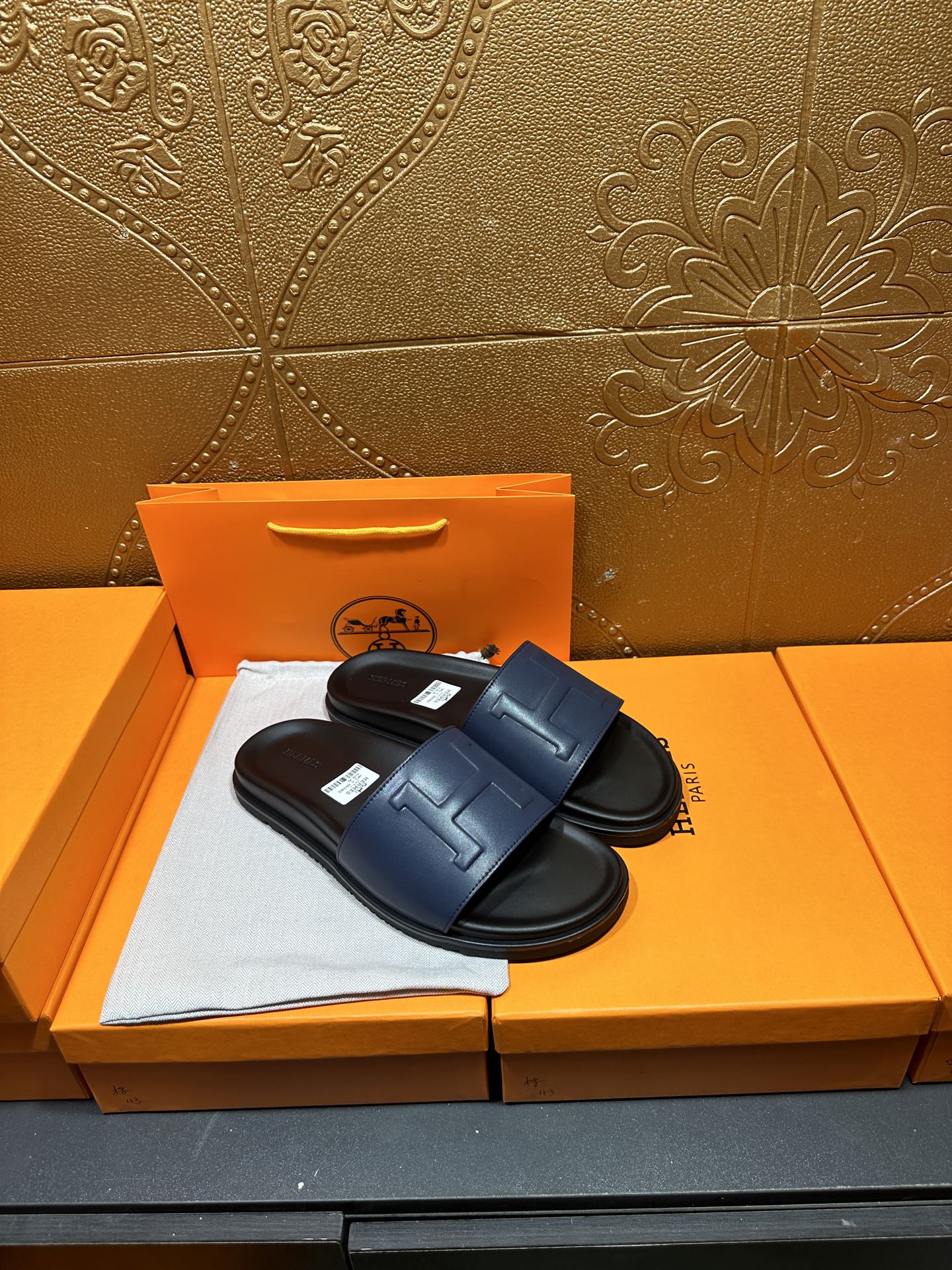 Leather slide sandals with broad strap, H stitch detail, and black footbed