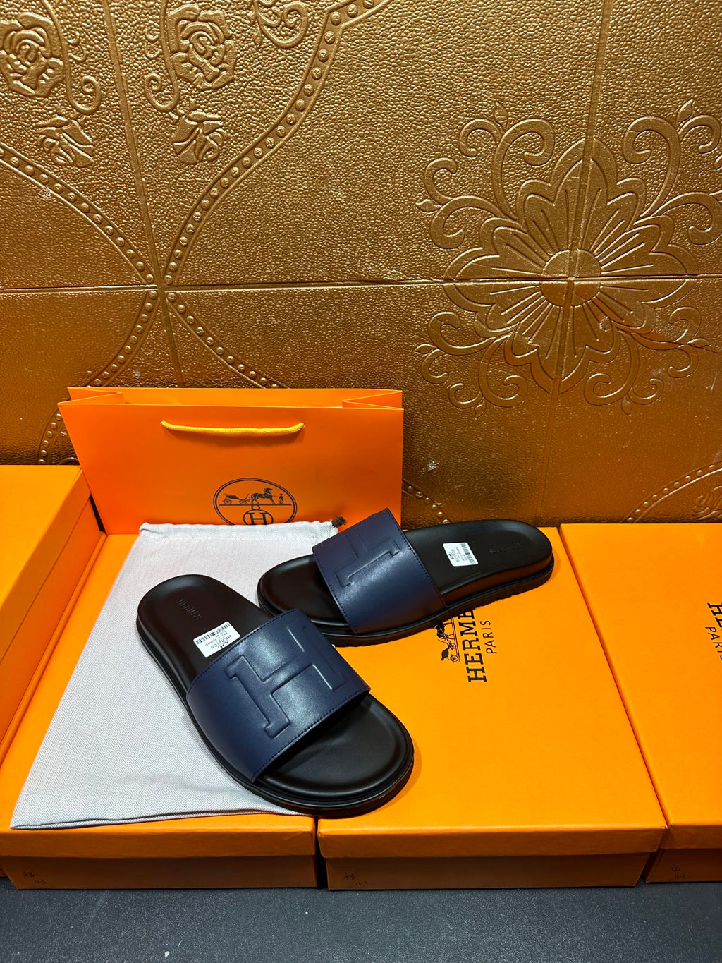 Pair of leather slide sandals with wide strap and embossed H detail on footbed