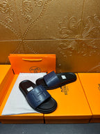 Pair of leather slide sandals with wide strap and embossed H detail on footbed