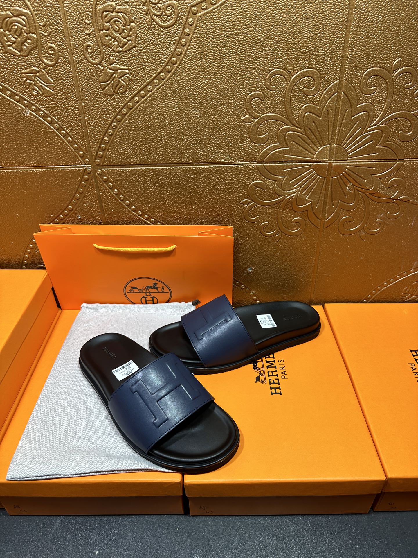 Pair of leather slide sandals with wide strap and embossed H detail on footbed