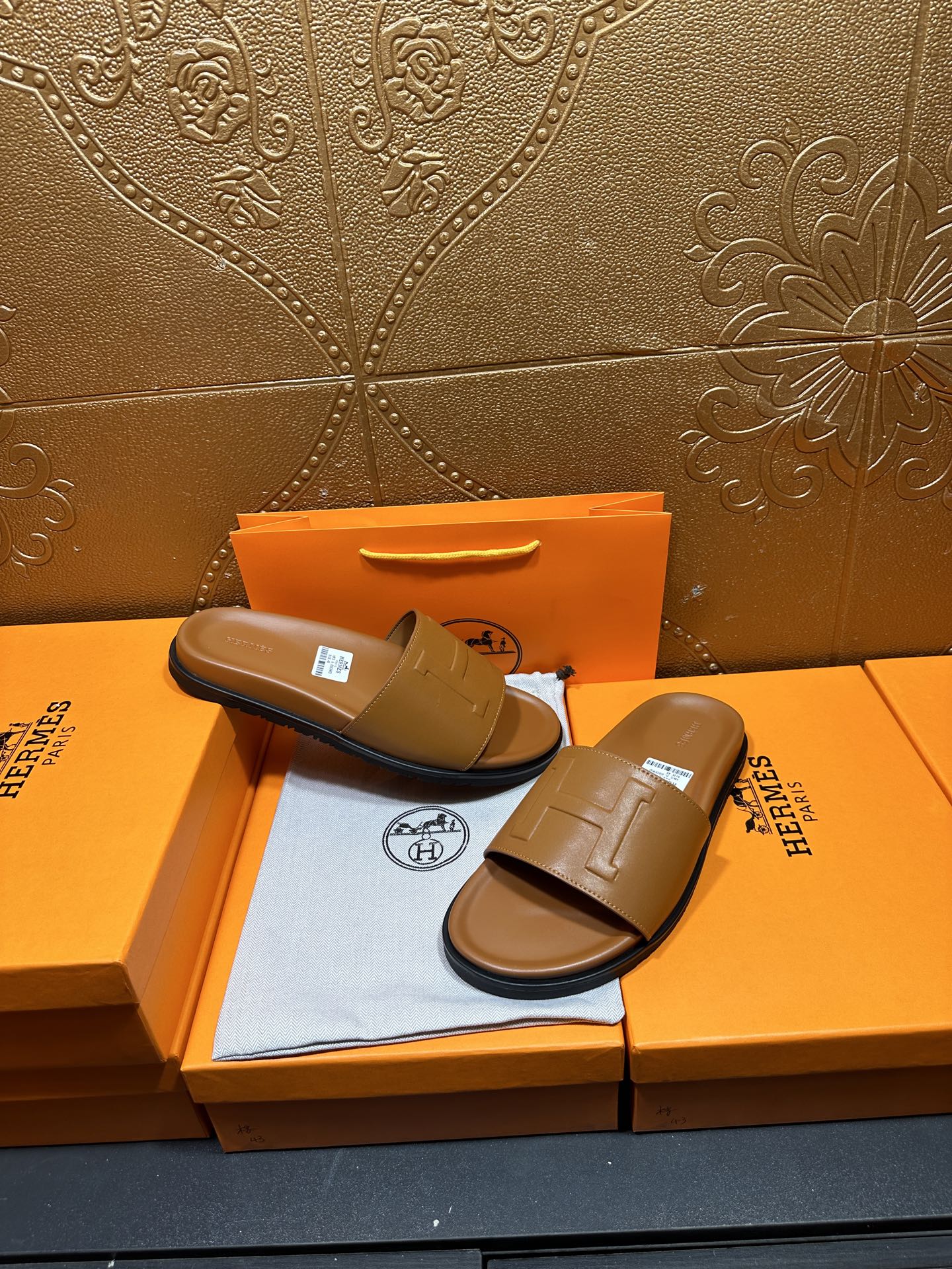 Tan leather Hermes slide sandals, one held back on box with square buckle strap