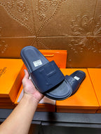 Hermes navy slide sandals close-up of molded H strap and footbed