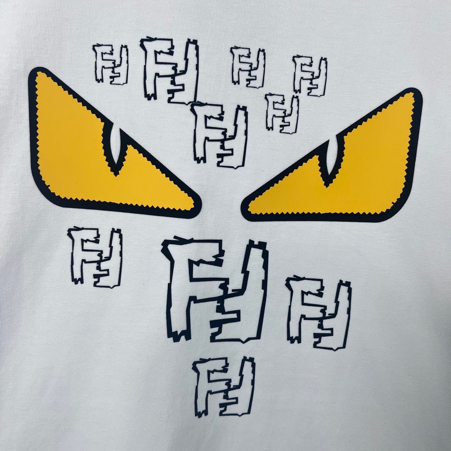 White sweatshirt front with large yellow eye graphic and black F-shaped letter symbols