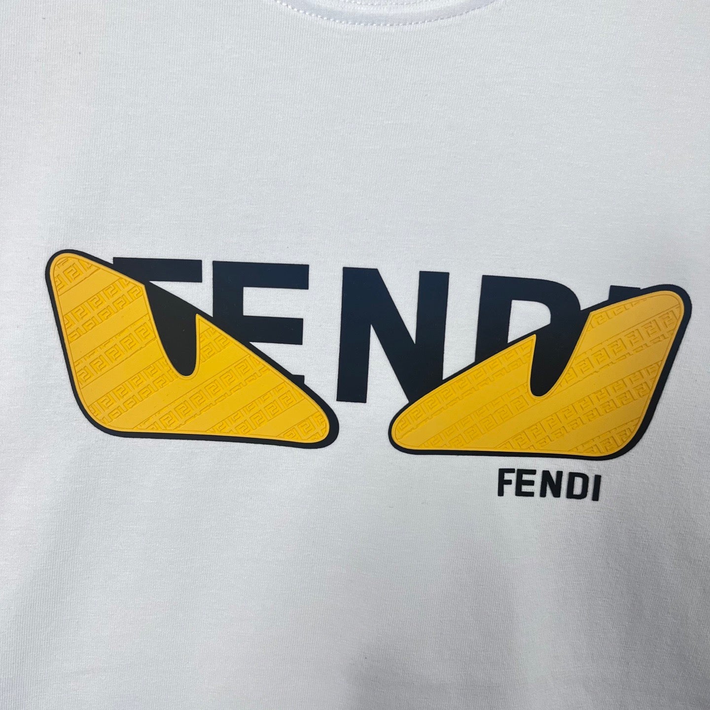 Close-up of white sweatshirt with FENDI text and yellow shield graphic