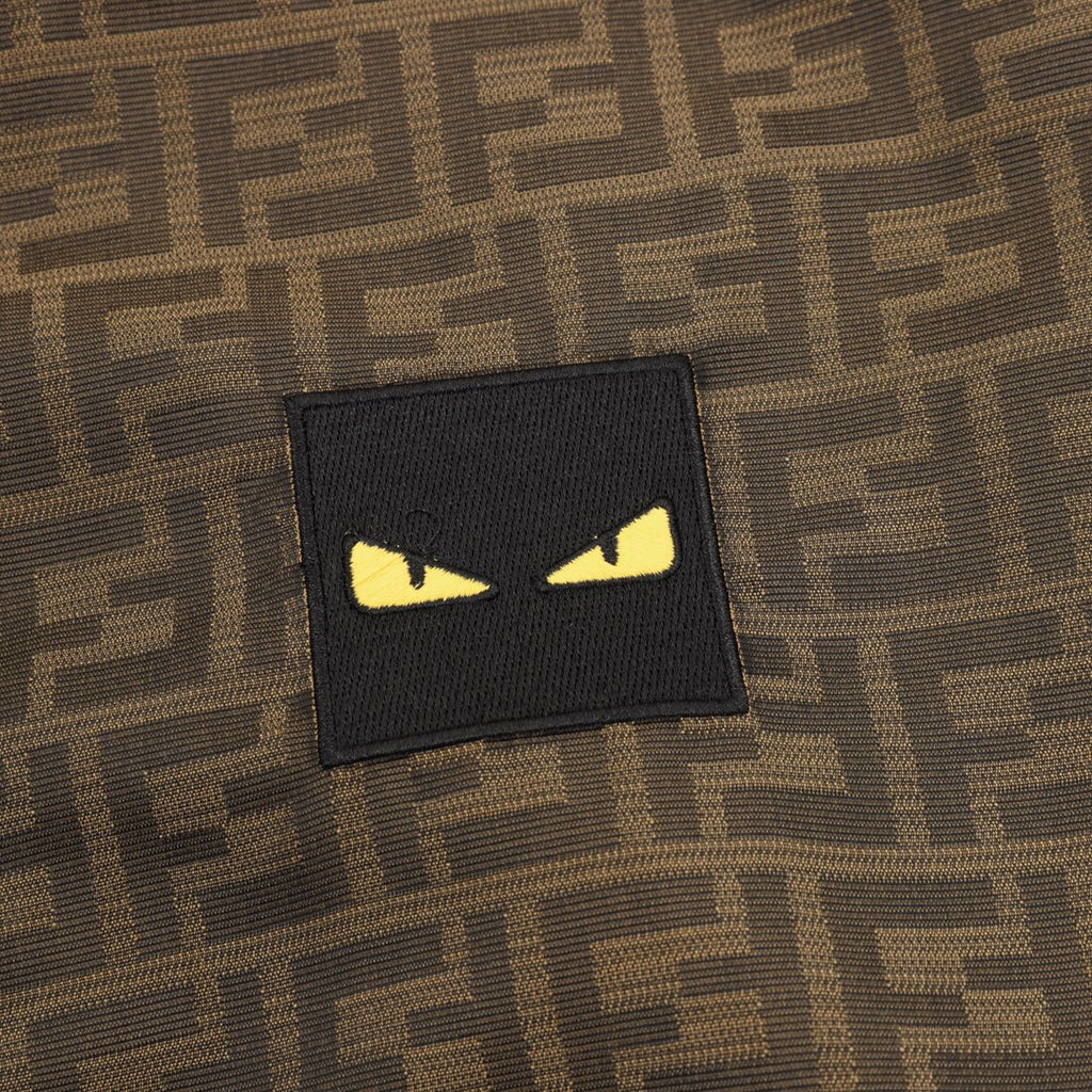 Black rectangular logo patch with yellow eyes on brown FF hooded jacket.