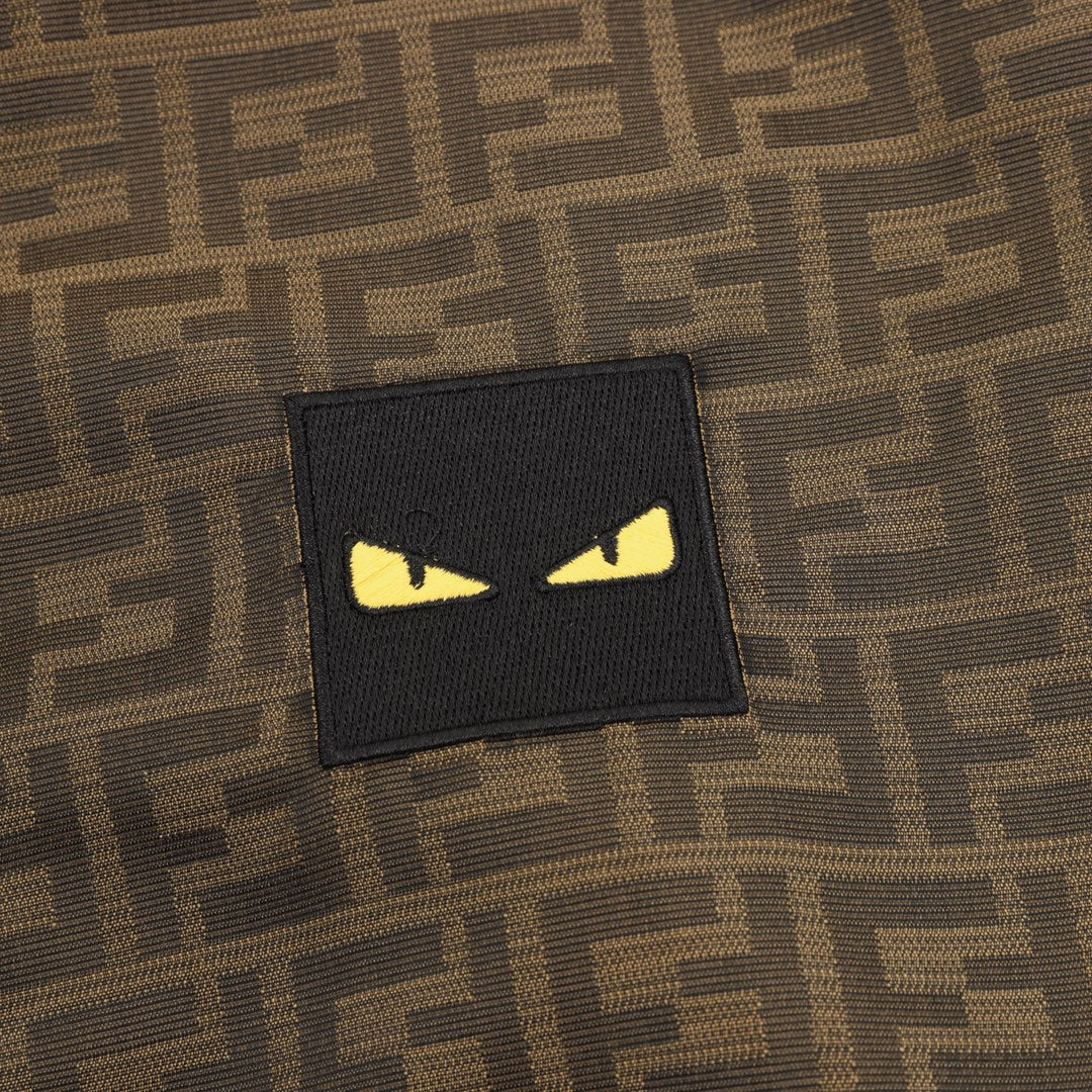 Black rectangular logo patch with yellow eyes on brown FF hooded jacket.