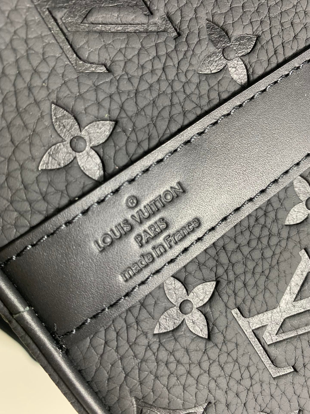 Embossed logo label on monogram duffel bag exterior