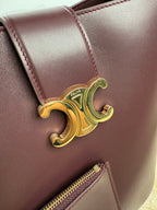 Celine burgundy leather bag with gold-toned logo ornament on front
