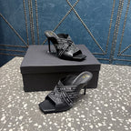 Black slide sandals with logo-print upper, open toe, and stiletto heel set on box