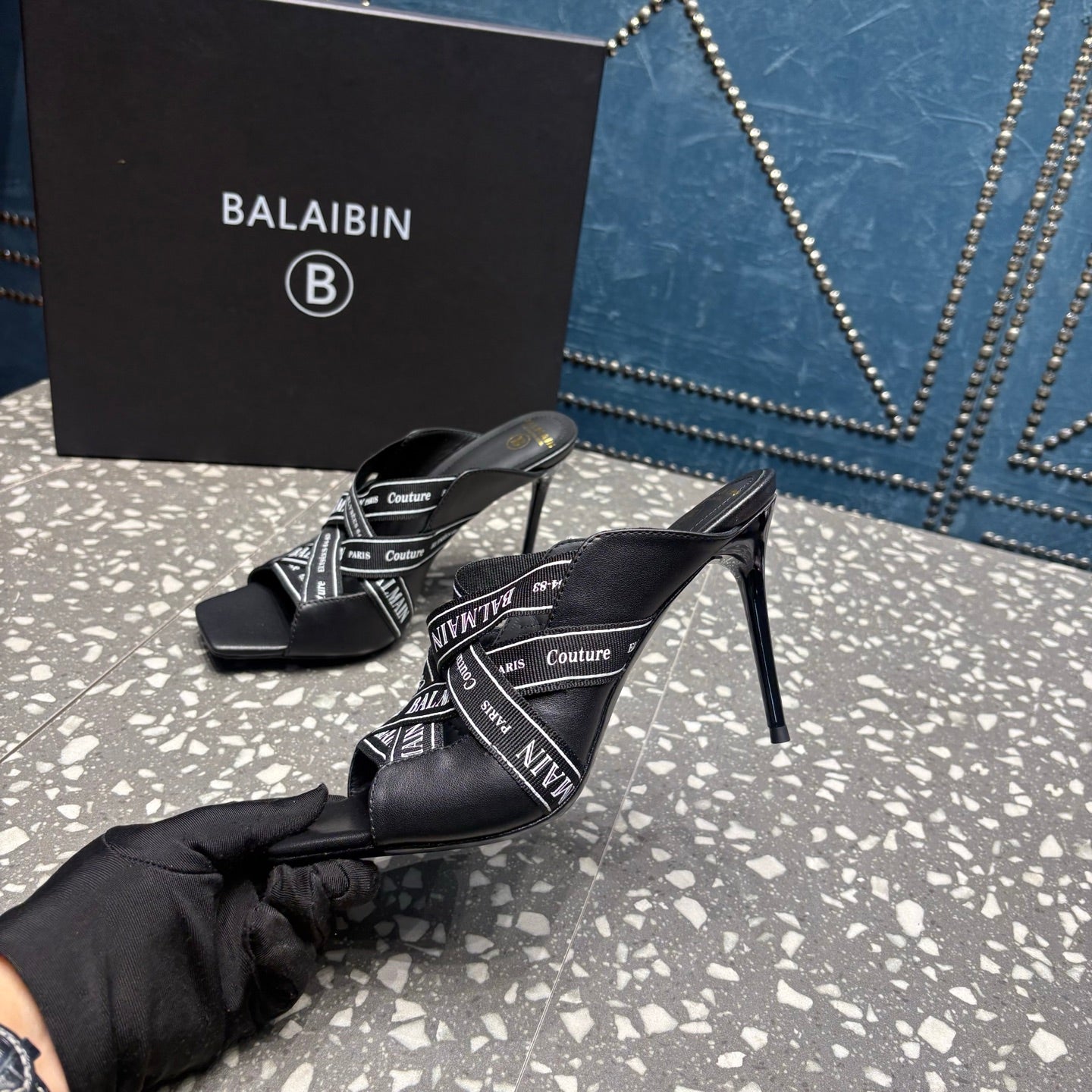 Black slide sandals with open toe, logo-print upper, and tall stiletto heel