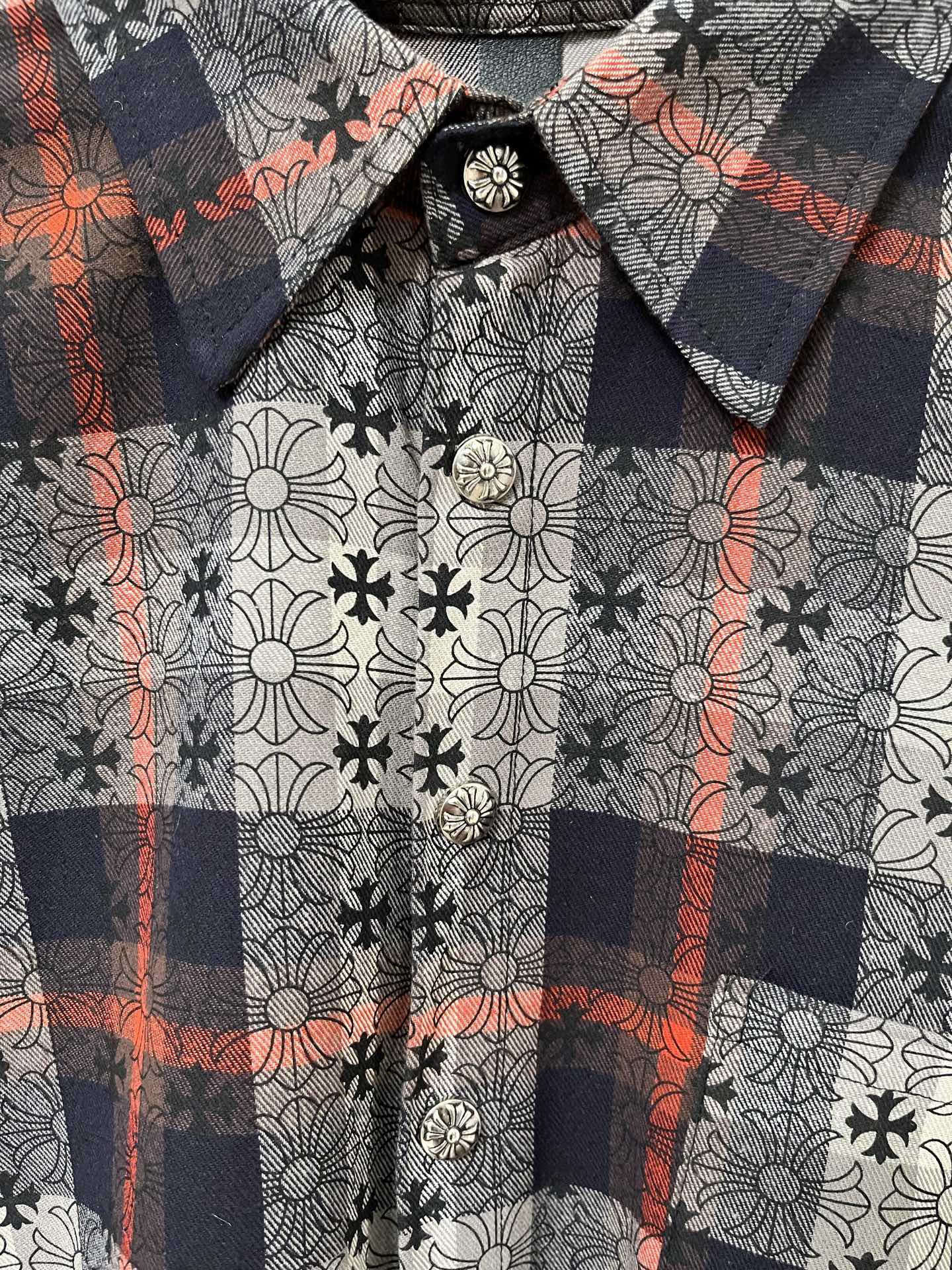 Shirt neckline detail with floral-and-plaid pattern and round button