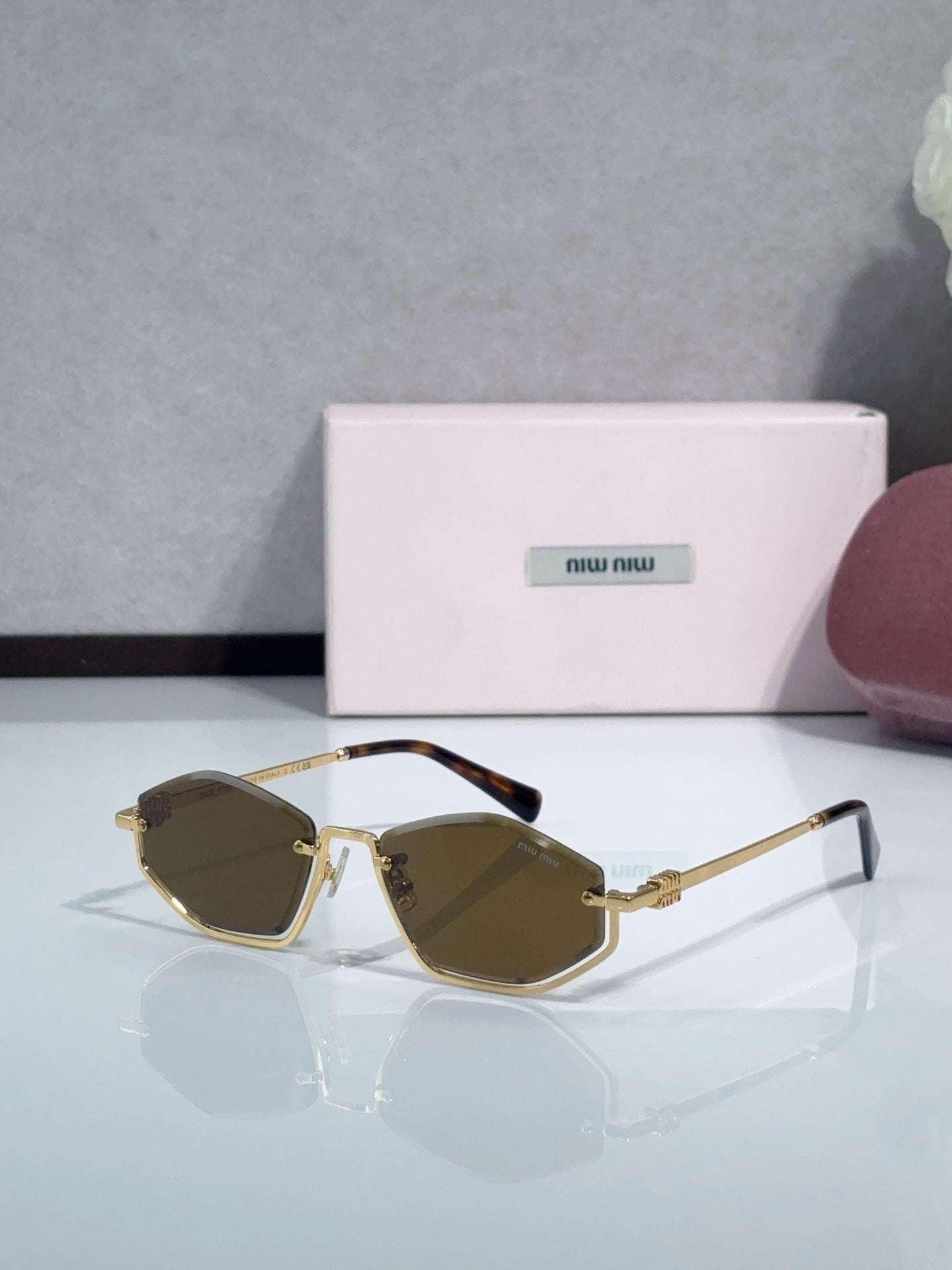 Miu Miu sunglasses with brown lenses, gold-tone frames, and dark brown temple accents
