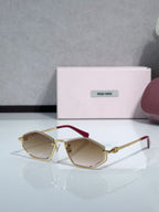 Miu Miu sunglasses with tan lenses, gold-tone octagonal frames, and red temple accents
