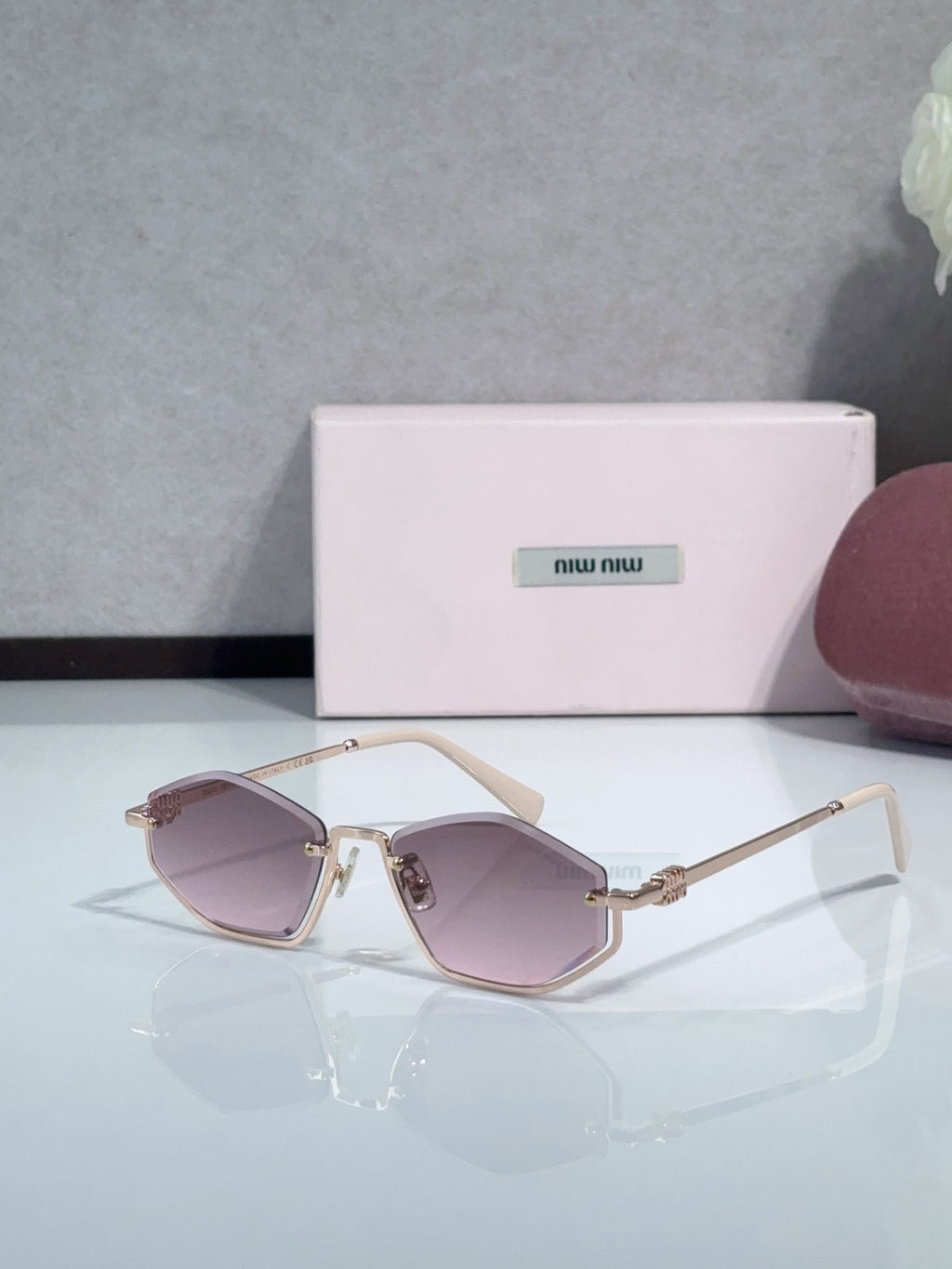 Miu Miu sunglasses with pink lenses, gold-tone frames, and pale pink temple tips