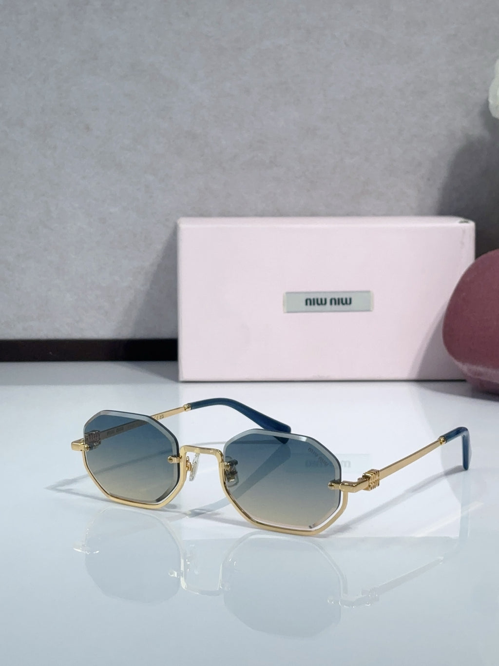 Gold metal hexagonal sunglasses with light blue lenses and navy temple detailing