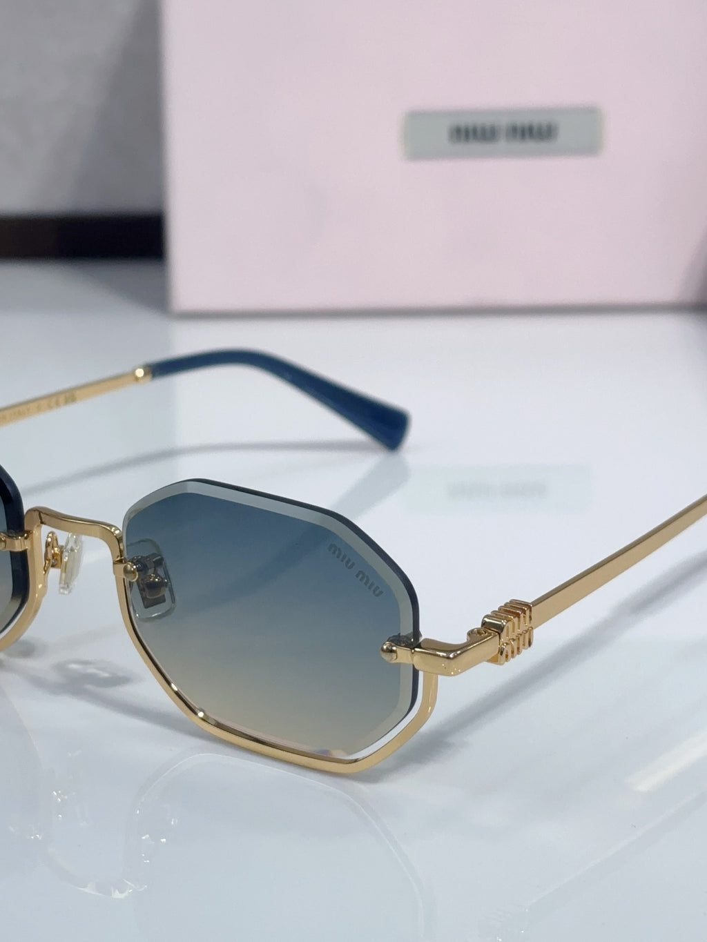 Gold hexagonal sunglasses with dark blue lenses and blue acetate temple arms