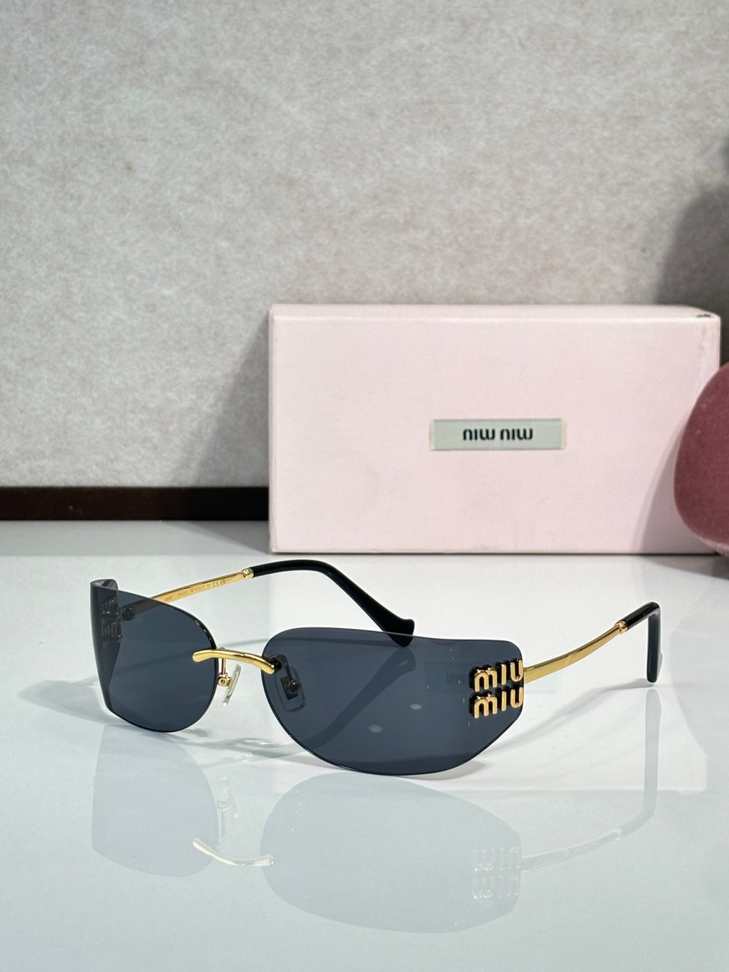 MiuMiu sunglasses with dark blue lenses, black frame, gold-tone temples