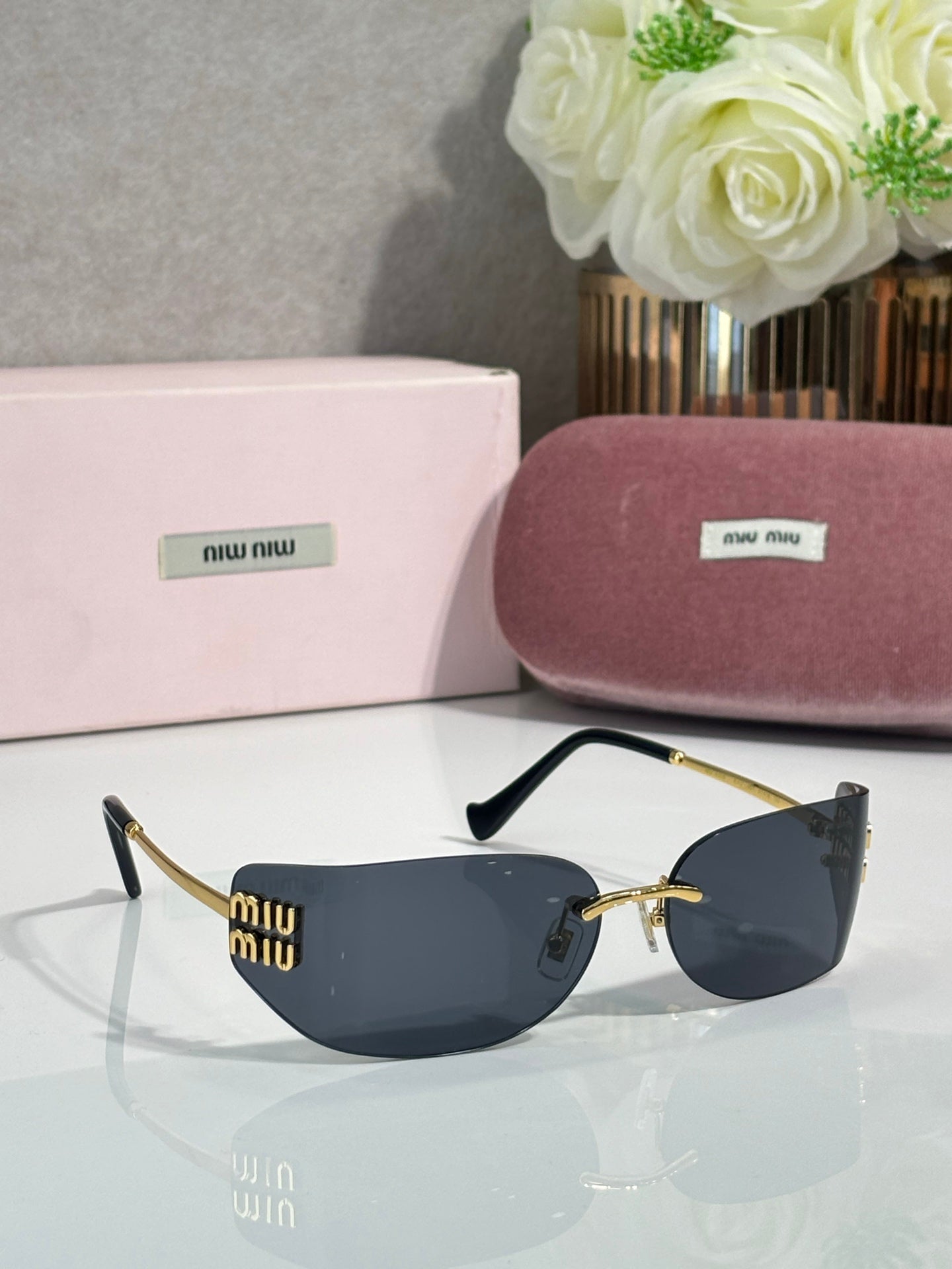 MiuMiu sunglasses with dark blue lenses, gold frame and black details