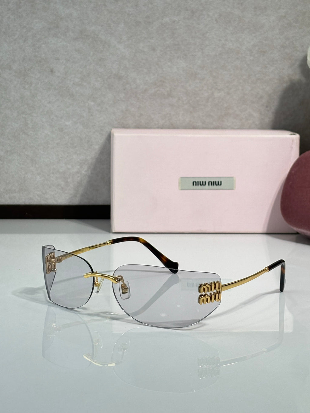 MiuMiu sunglasses with clear lenses, gold frame, black temple tips