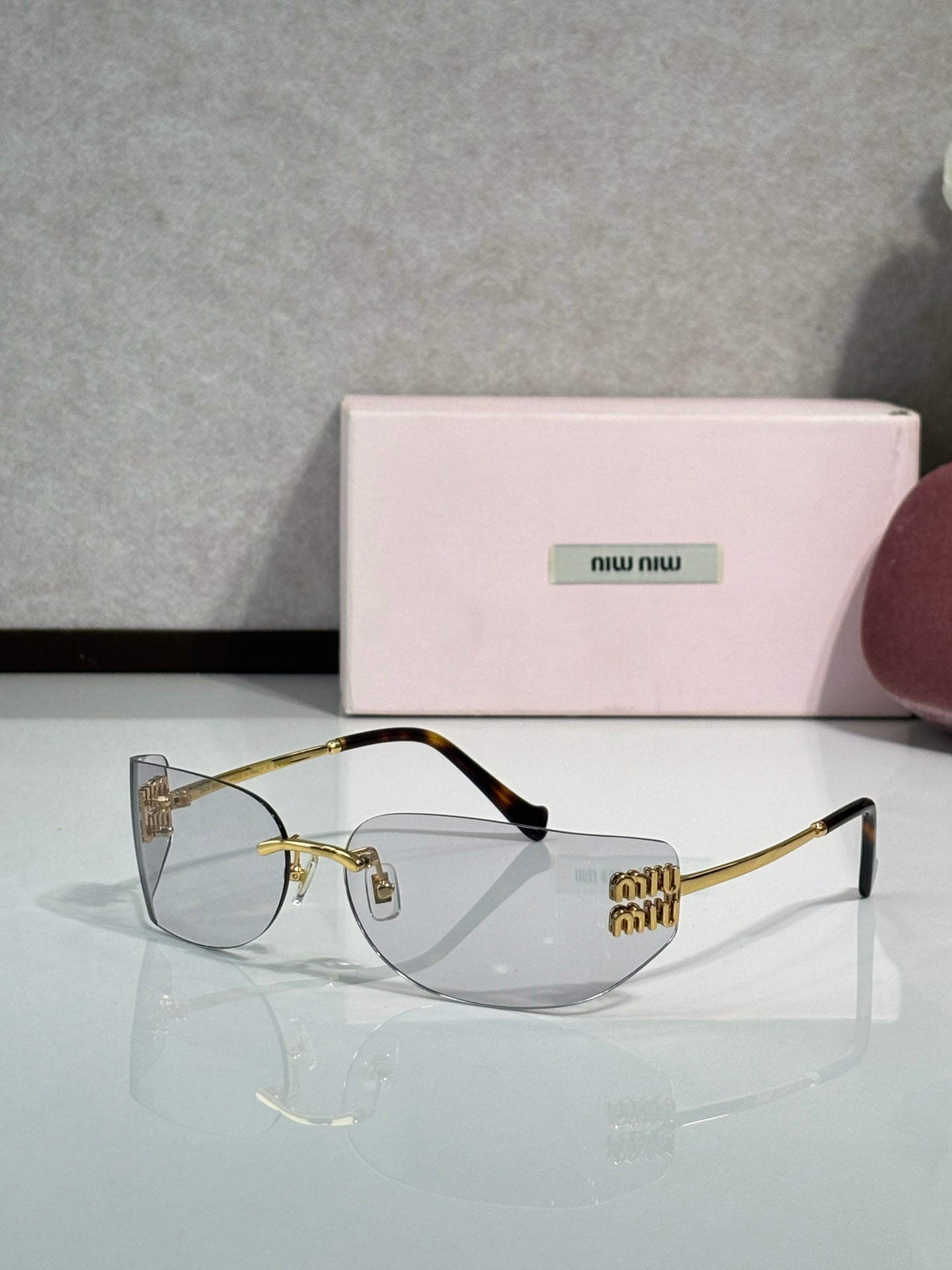 MiuMiu sunglasses with clear lenses, gold frame, black temple tips