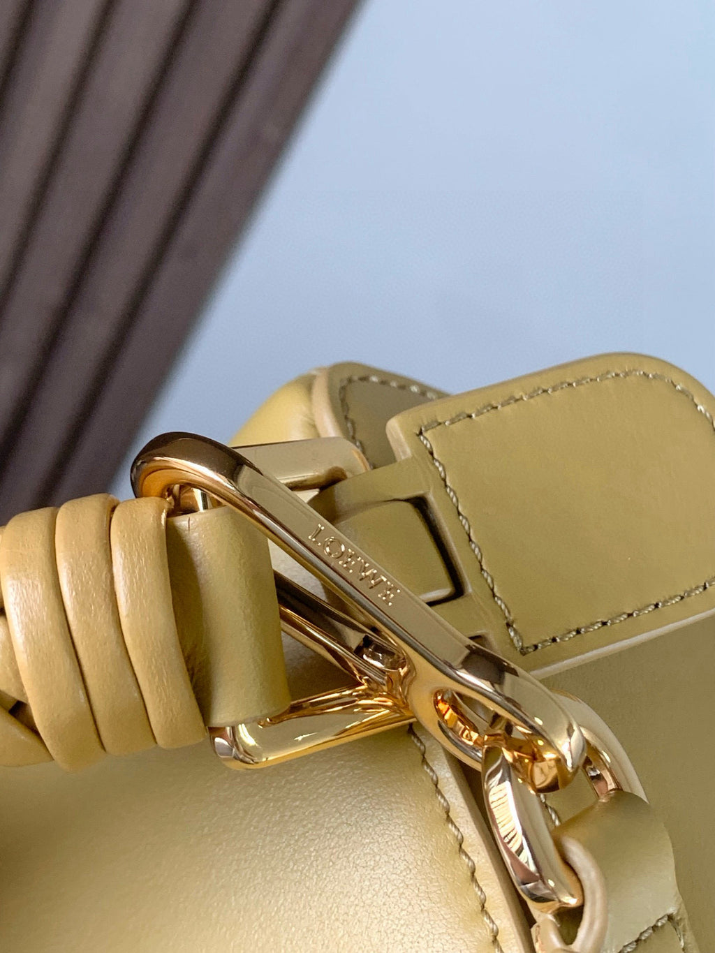 Loewe light yellow leather bag close-up of gold clasp and braided strap connection