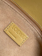 Loewe light yellow leather bag close-up of embossed Loewe logo patch near zipper