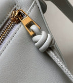 Light blue leather bag detail with gold clasp and knotted zipper pull tab