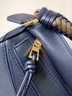 Blue leather bag corner with braided strap and gold zipper pull detail