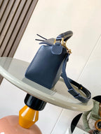 Blue leather crossbody bag with short strap, braided handle, and gold clasp