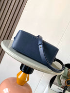 Blue leather tote-style bag with adjustable shoulder strap and gold trim