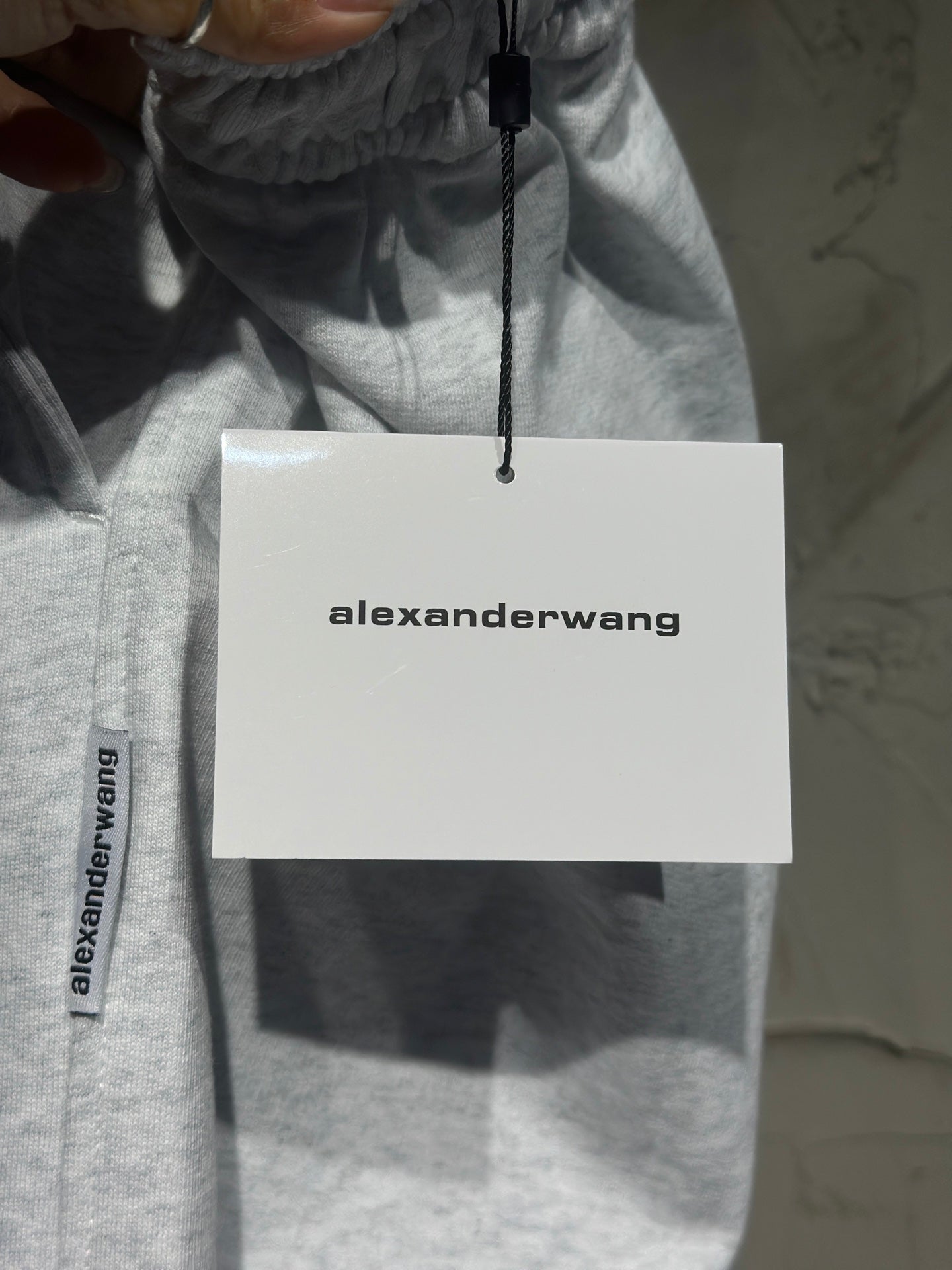 Heather-gray sweatpants with alexanderwang hang tag attached to the waistband.