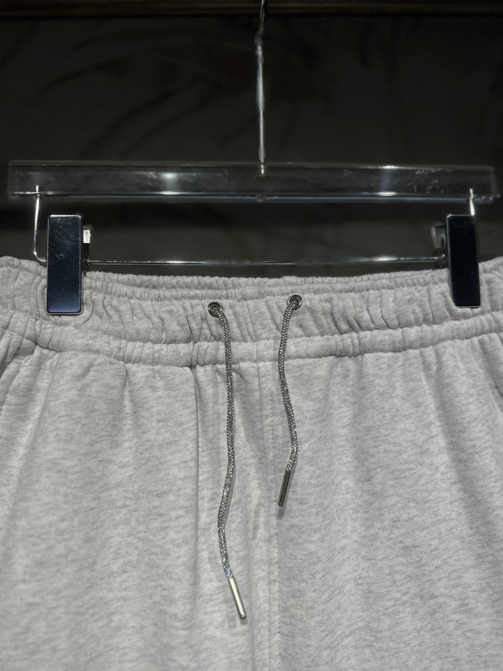 Heather-gray sweatpants waistband close-up with drawstring cords and elastic back.