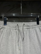 Heather-gray sweatpants waistband close-up with drawstring cords and elastic back.