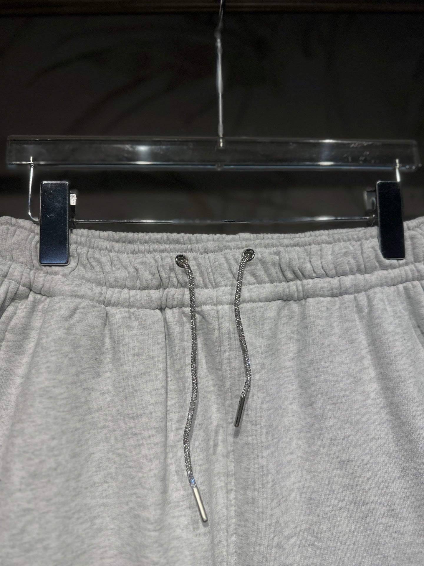 Heather-gray sweatpants waistband close-up with drawstring cords and elastic back.