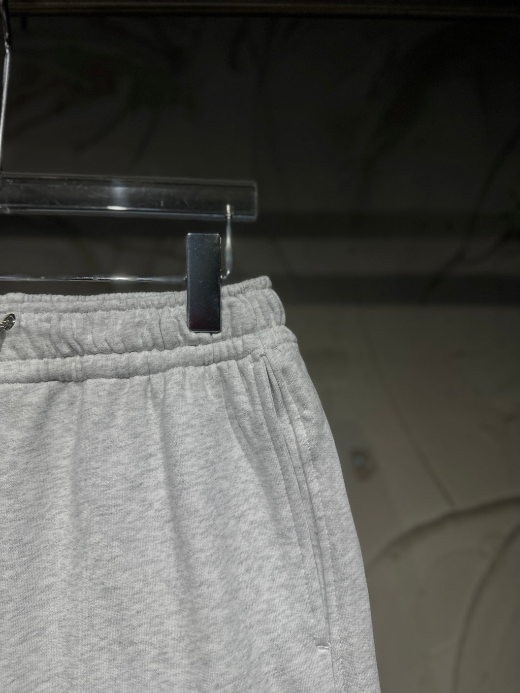 Heather-gray sweatpants waistband close-up with elastic band and stitched seam.