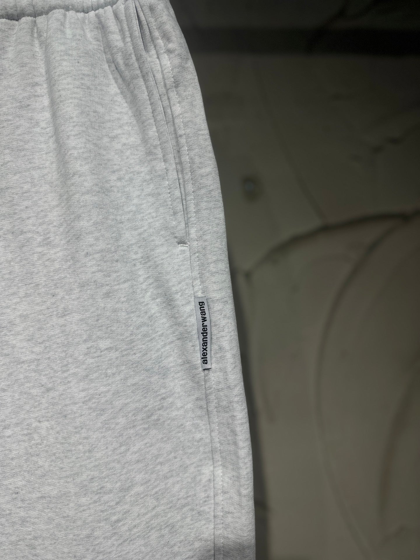 Heather-gray sweatpants with vertical side logo label and relaxed straight-leg fit.