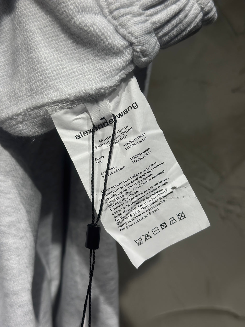 Heather-gray sweatpants with interior care label showing care and composition text.