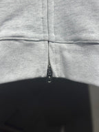 Light gray hoodie front zipper close-up at chest with stitched seam