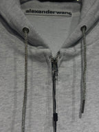 Light gray hoodie close-up with front zipper and dark zipper pulls on drawstring