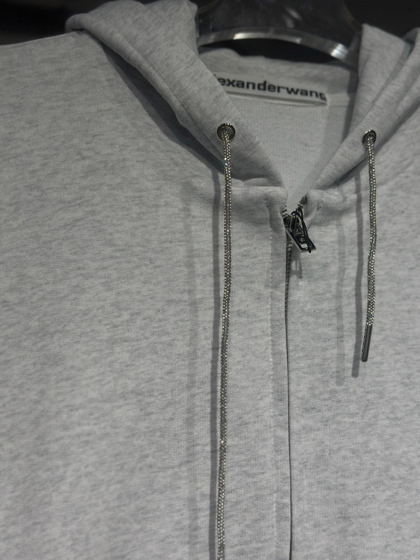 Light gray hoodie with front zipper and metallic chain drawstrings at hood