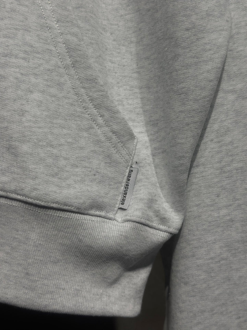 Light gray hoodie sleeve cuff with small printed label tag
