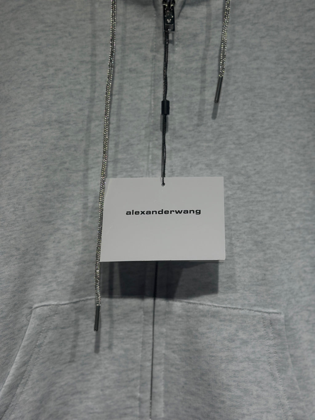 Light gray hoodie with dangling zipper pulls and white alexanderwang hang tag