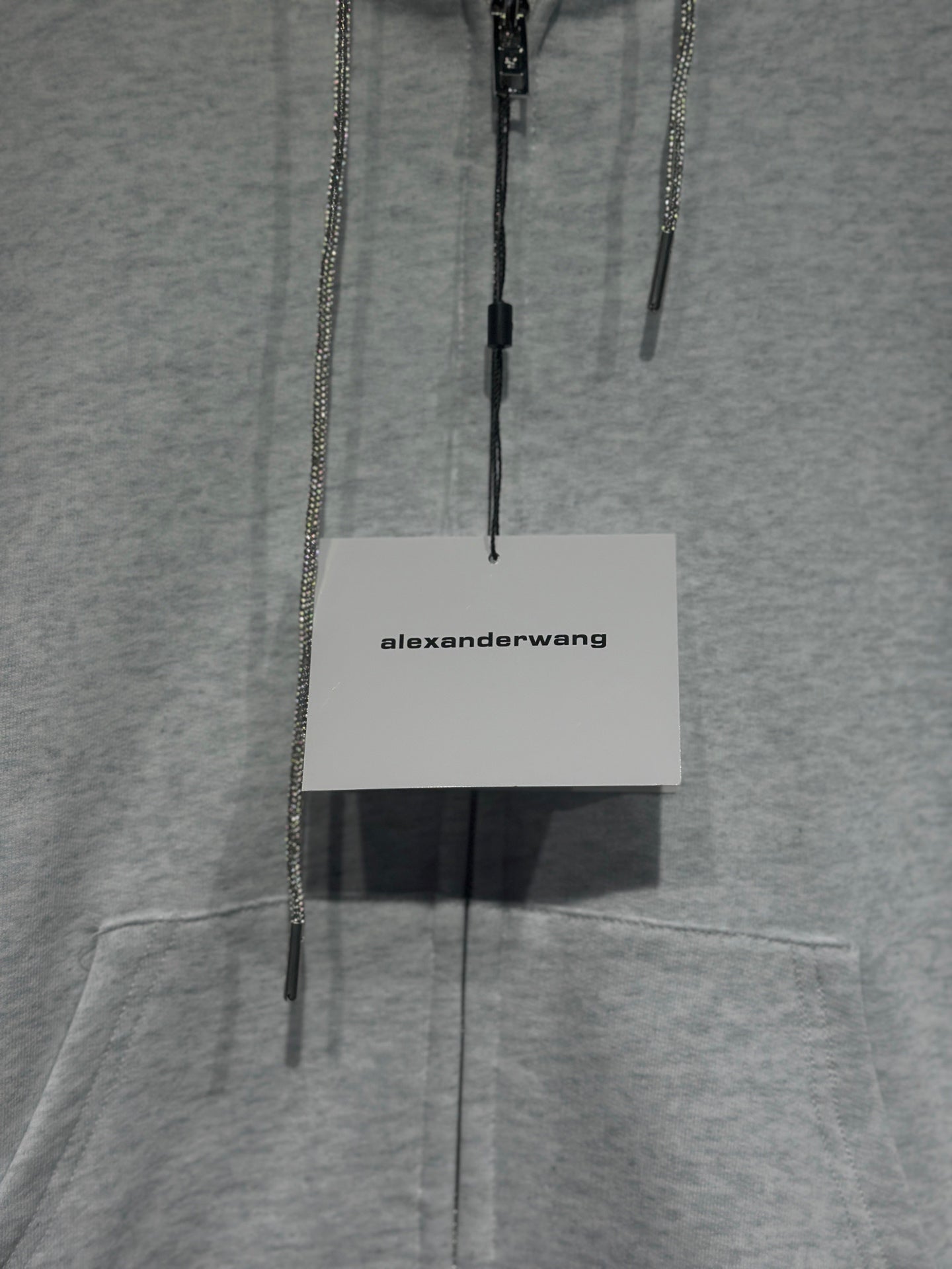 Light gray hoodie with dangling zipper pulls and white alexanderwang hang tag